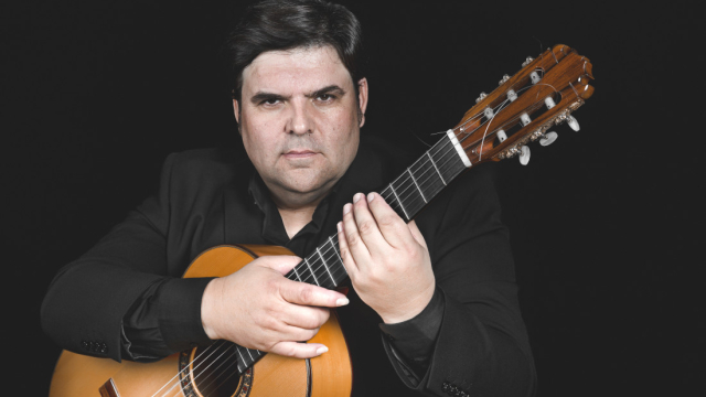 Guitarrista flamenco con guitarra española sobre fondo negro