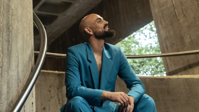 Hombre con traje azul sentado en una escalera interior de hormigón